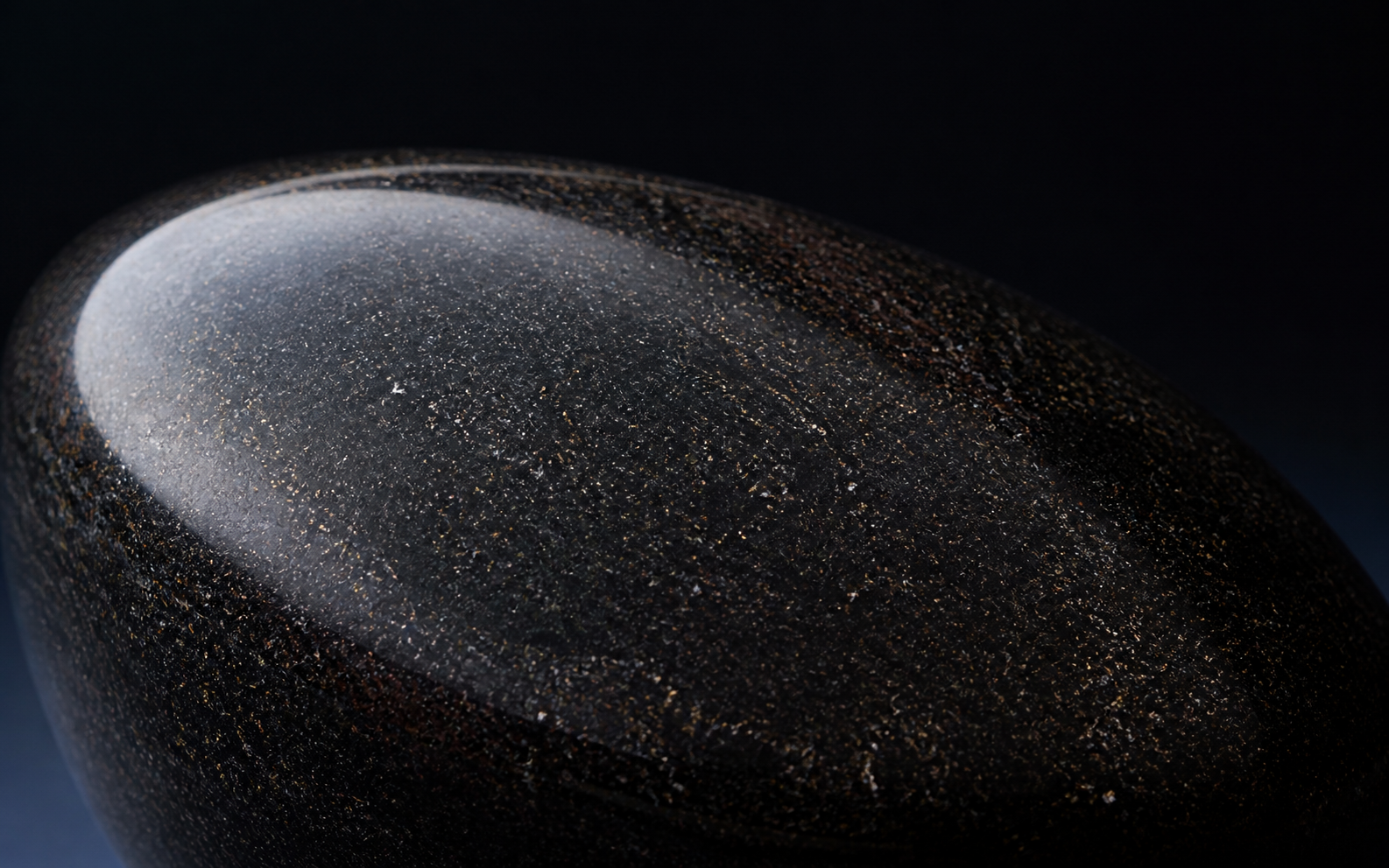 Close macro study of polished black aventurine with fine warm points of brilliance